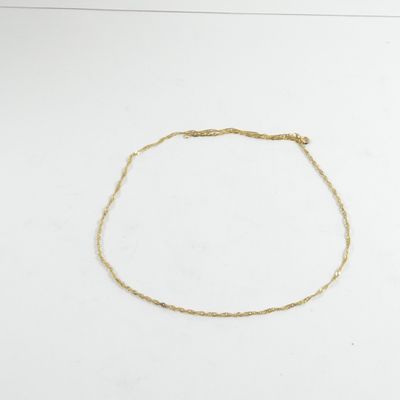 gros plan d'un bracelet en chaîne en or sur une surface blanche