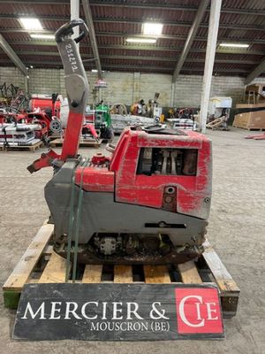 une machine rouge posée sur une palette dans un entrepôt