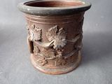 a brown vase with a design on it on a gray surface