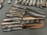 a lot of silver spoons and knives on the table