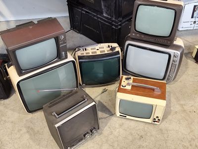 several old televisions are stacked on top of each other on the floor