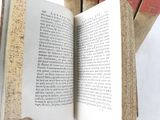 a person holding an open book in front of a stack of books