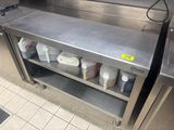 une étagère en acier inoxydable sur laquelle sont posées des bouteilles et des récipients