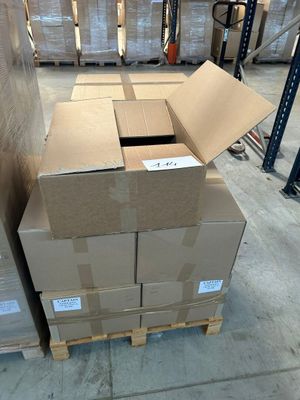 des cartons empilés sur des palettes dans un entrepôt, avec des palettes en arrière-plan