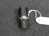 une bague sertie d'un diamant, posée à côté d'une étiquette de prix