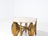 une table basse dorée avec un plateau en marbre sur un piètement blanc
