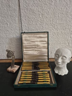 an open box of pens sitting on top of a table next to a statue of a head