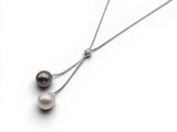 un gros plan sur un collier auquel sont suspendues deux perles
