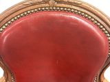 a red leather chair with a gold frame on the back
