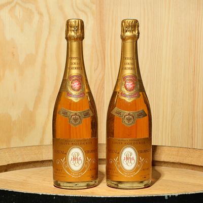 two bottles of champagne sitting on top of a wooden barrel