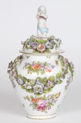 a white vase with a figurine sitting on top of it
