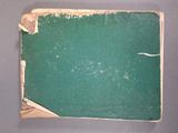 un livre vert aux pages déchirées posé sur une table