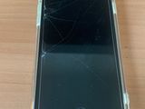 an iphone with a cracked screen sitting on a wooden table