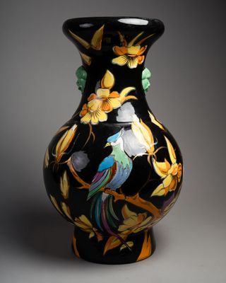 un vase noir sur lequel sont peints un oiseau et des fleurs