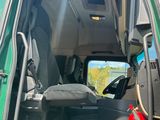 a green truck with the door open and the driver ' s seat down
