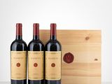 three bottles of red wine in front of a wooden box