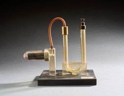 une image représentant une bouteille en verre contenant un liquide, posée sur un socle en bois
