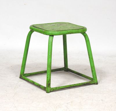 un vieux tabouret vert posé sur un sol blanc