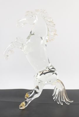 figurine de cheval en verre transparent posée sur une surface noire avec un fond blanc