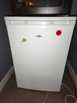 a small white refrigerator with a red button on it