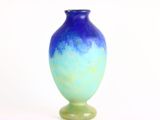 un vase bleu et vert posé sur une surface blanche