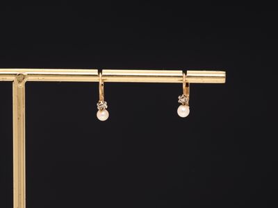 a pair of gold earrings with pearls hanging from them