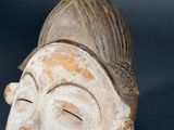 a wooden sculpture of a woman ' s face on a black background