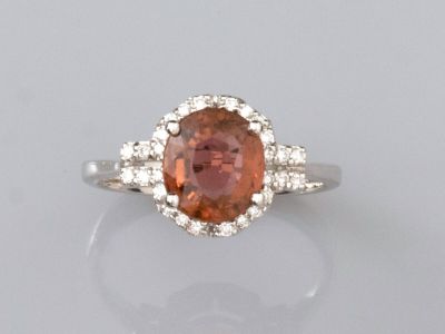 un gros plan d'une bague ornée d'une pierre orange entourée de diamants blancs