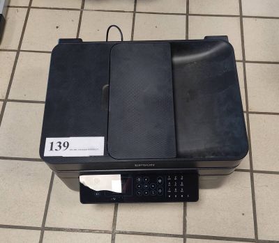 une imprimante noire posée sur un sol carrelé, avec une étiquette de prix
