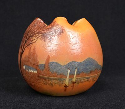 an orange vase with a picture of a mountain scene on it
