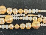 gold and white beaded bracelet with pearls on a black surface