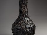 a black vase sitting on a table with a gray background