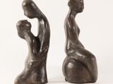 pair of bronze sculptures of a man and woman sitting on a ball