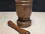 an old wooden mortar and a wooden mallet sit on a table