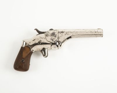 un vieux pistolet avec une poignée en bois sur une surface blanche