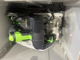 a black and green corded drill in a white cabinet