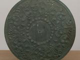 an old green metal plate with a circular design on it