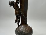 a bronze statue of a boy climbing on a vase