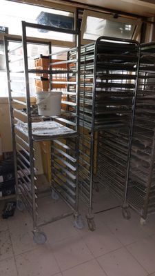 a man standing next to a rack of trays in a kitchen