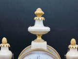 a white and gold clock sitting on top of a table