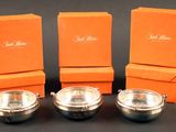 trois bols argentés avec des carrés orange sur un fond noir