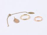 three gold rings and a necklace on a white surface