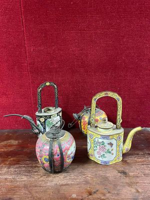 two small teapots sitting on a table next to each other