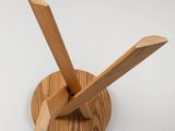 a wooden clock on a stand on a white surface