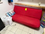 a red futon couch in the corner of a room