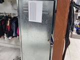 un petit réfrigérateur dans un coin d'une pièce, avec des vêtements sur les étagères