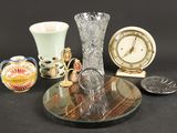 une table en verre sur laquelle se trouvent une horloge, un vase et d'autres objets