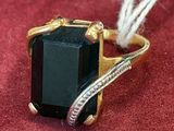 an image of a ring with a black stone on a red surface