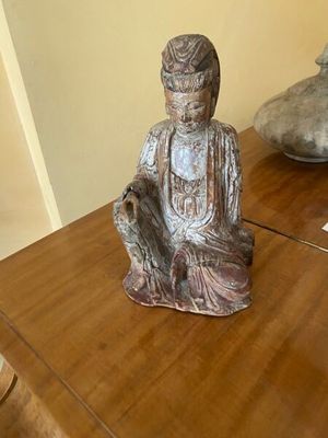 une statue représentant une personne assise sur une table en bois