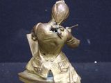 a gold statue of a man with a hat and jacket